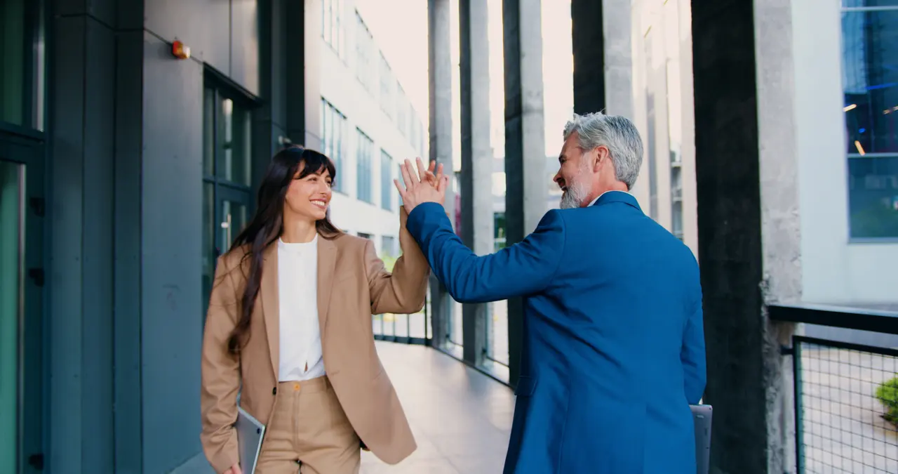 Two colleagues greeting each other outside a London office building.